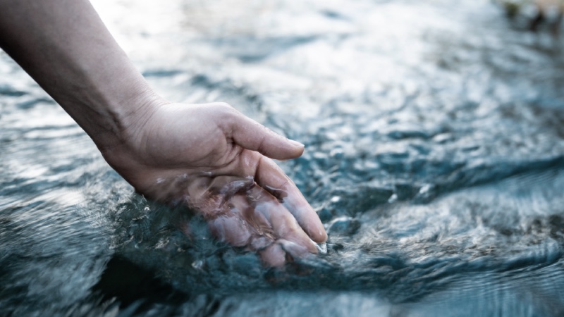 Hand gently touching water surface symbolizing calm, anxiety relief, stress reduction and somatic therapy